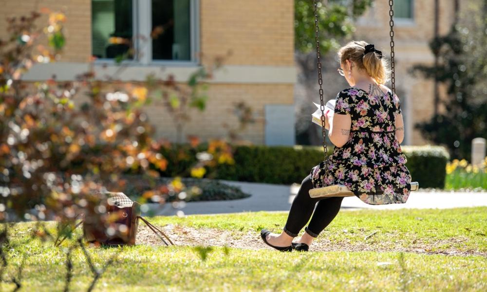 female student in swing on campus